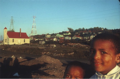 A person posing for the camera with the Africville Chrurch in the background.