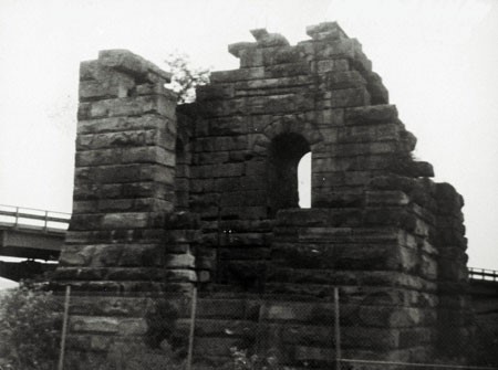 A black and white photograph of the ruin of the Cornish pumphouse, erected by the General Mining Association in 1866 to house the pumping mechanism for the Foord pit. The ruin is made of sandstone blocks and an arched opening is still in place. The photograph was taken in 1987, prior to the dismantling of the ruin.