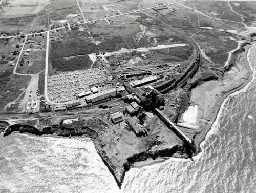 : A modern black and white photograph of an aerial view of Number 26 colliery, Glace Bay, 1977, showing its proximity to the Atlantic Ocean. 