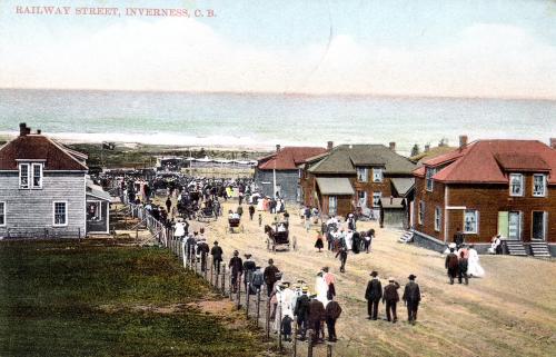 colour postcard of Railway Street in Inverness, circa 1920. Miners housing is shown and many people and some horses and buggies are headed toward the shore.