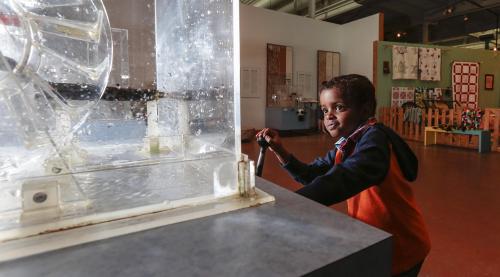 Small child playing at the interactive water power exhibit at the Museum of Industry.