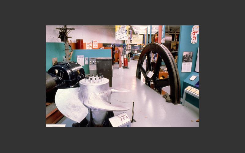 The shiny artifact on the left in our electricity exhibit is a Kaplin water turbine runner. It was from a hydroelectric power plant at Cowie Falls, Queen’s Co., NS. and represents one of the ways we create electric power.