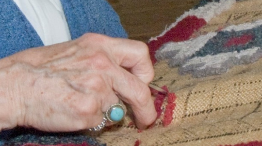 Close up of hands rug hooking.