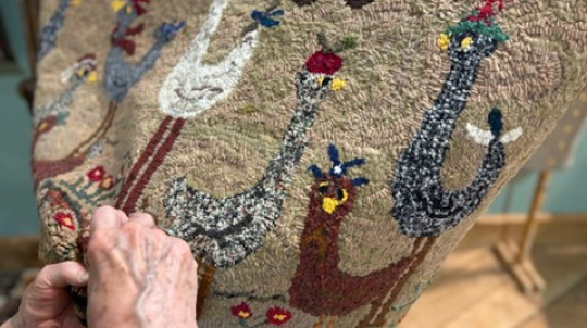 Cloe up of hands rug hooking birds.